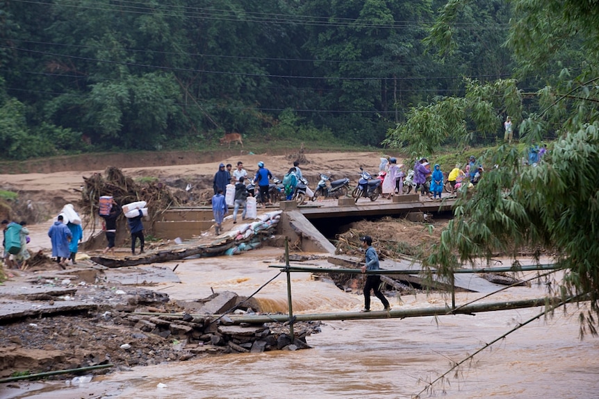 Residents carrying relief packages through a collapsed bridge leading to Van Ry village, Huc Commune, Huong Hoa district.