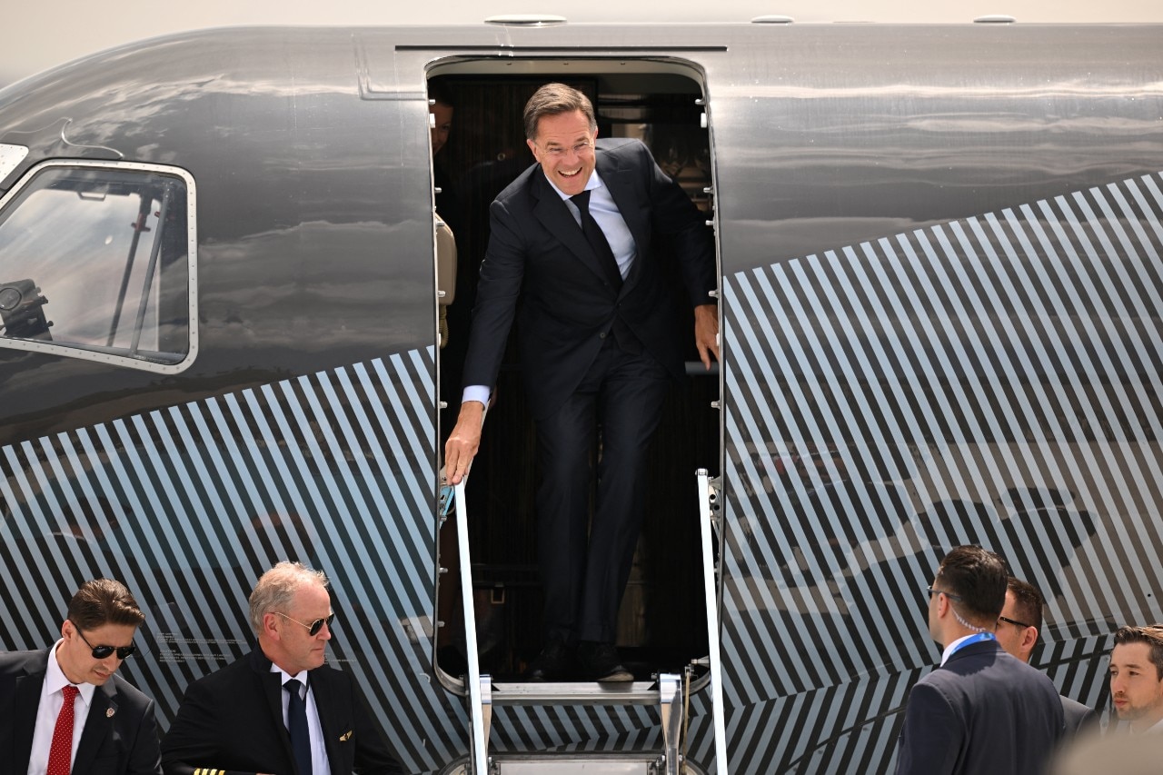 Un hombre de traje sale de un avión y sonríe.