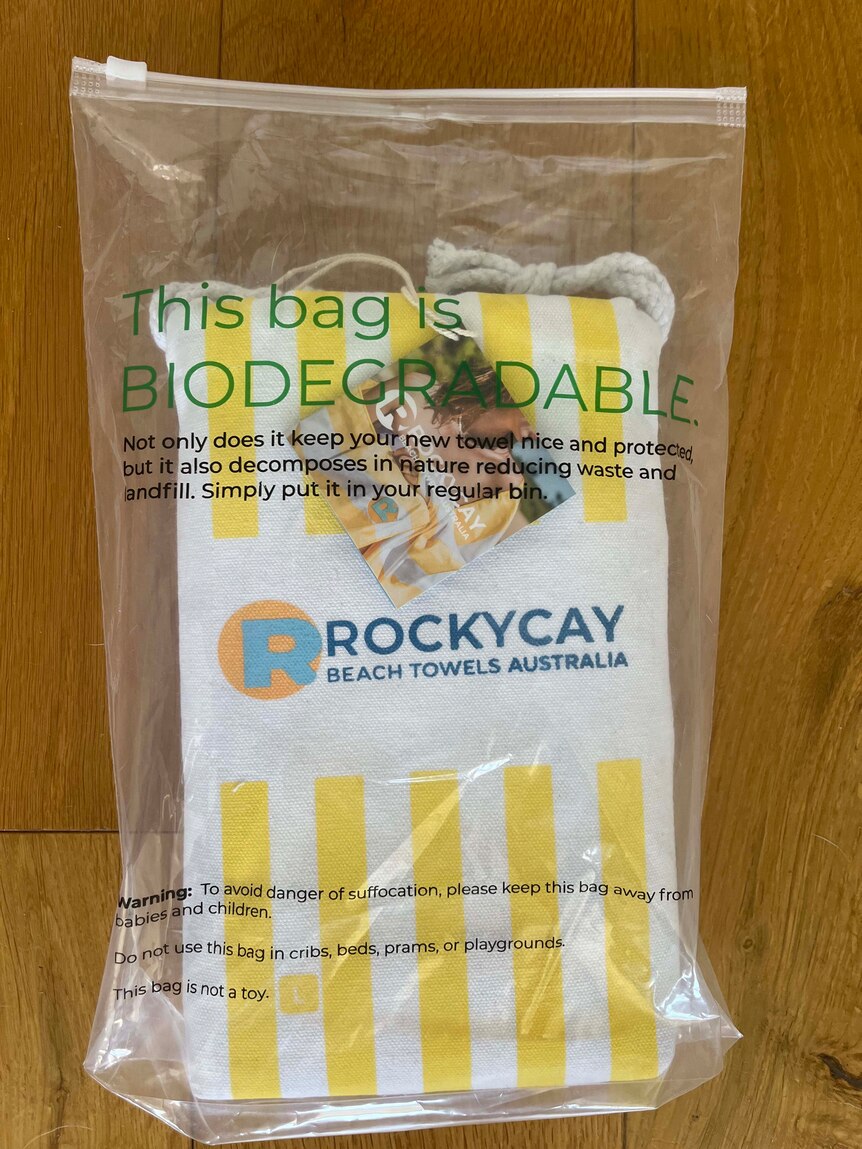 A yellow stripped towel inside a plastic ziplocked bag printed with "this bag is biodegradable".