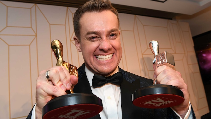 Grant Denyer holds up his silver and gold logies