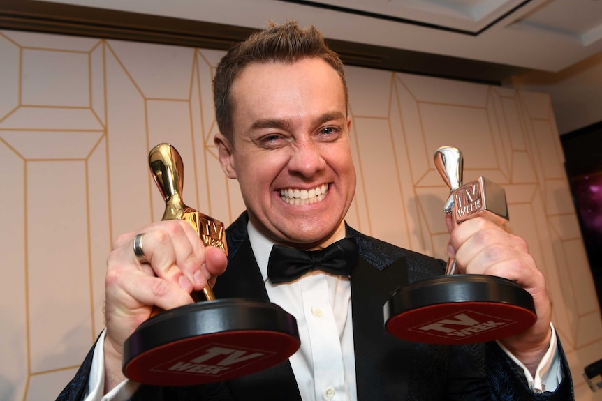 Grant Denyer holds up his silver and gold logies