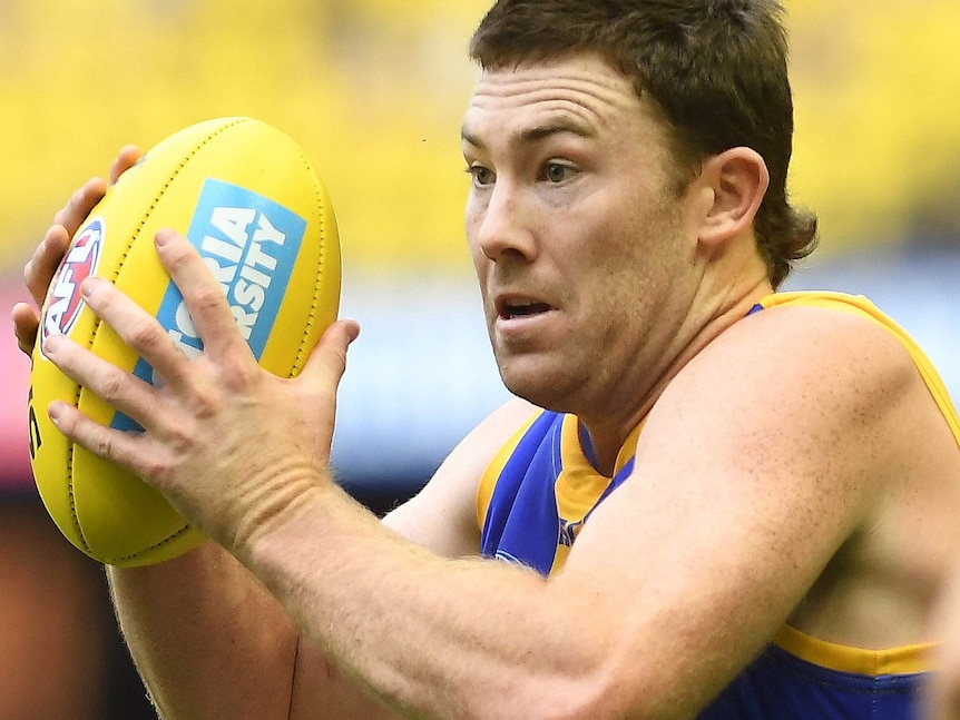 A West Coast Eagles player holds the ball and runs.