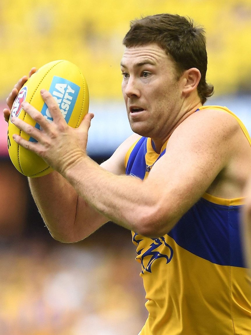A West Coast Eagles player holds the ball and runs.