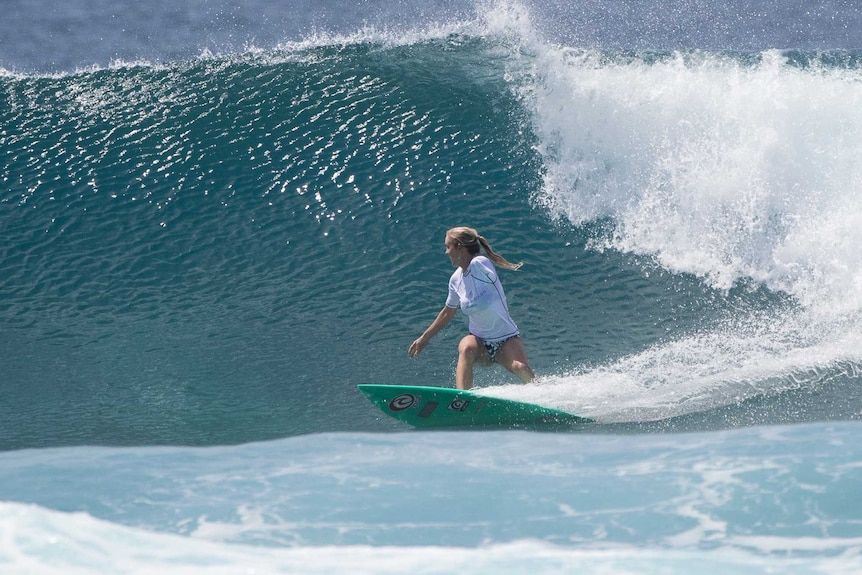 A woman with one arms surfs a large wave.