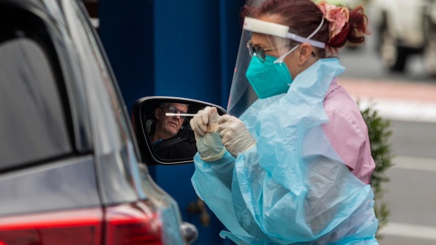 A woman in a mask and plastic coat tests drive in car.