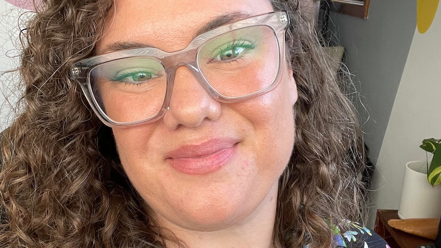 A woman wearing glasses smiles at the camera.