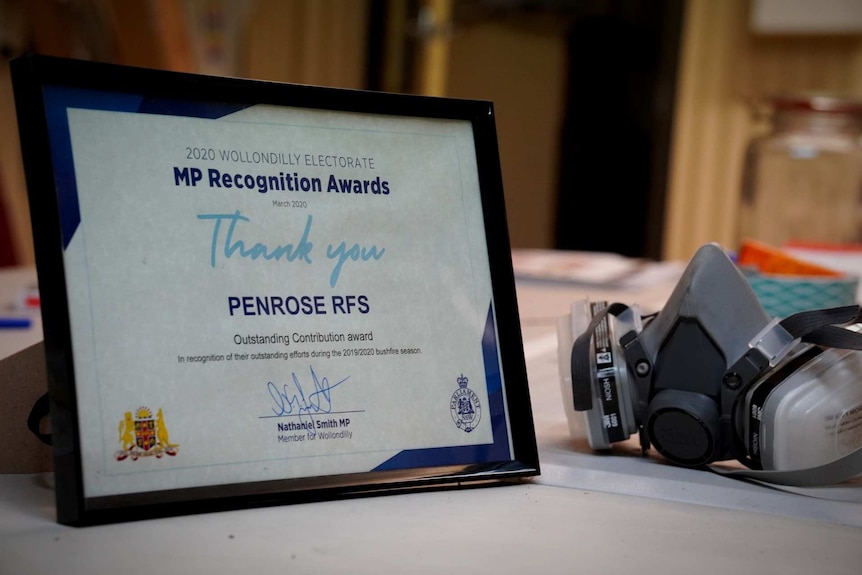 A framed certificate to the Penrose RFS  sits on a table next to a gas mask.