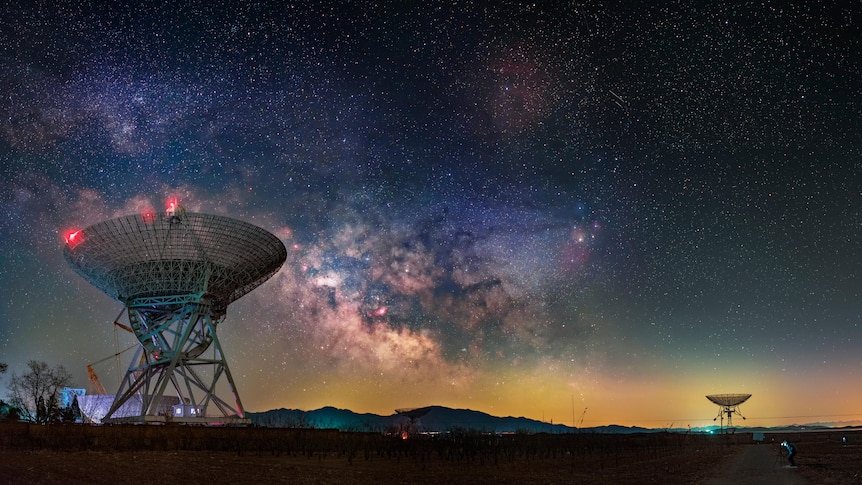 Large radio telescopes in the outback with a star filled sky.