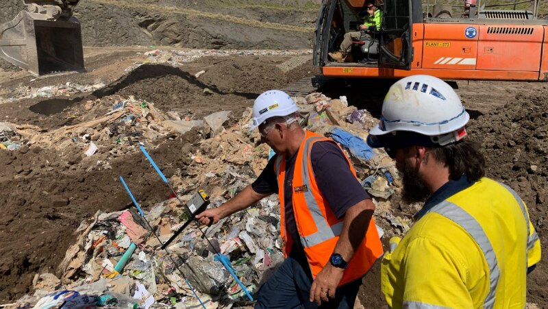 Two men sift through garbage at a tip