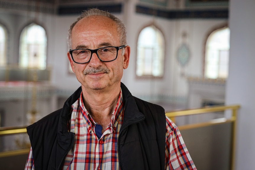 A portrait photo of a man in a mosque. 