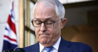 Malcolm Turnbull frowns, with his eyes cast downward, at a press conference in a courtyard