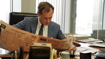 Jude Law in an 80s suit looking at a newspaper stressed in the film The Nest