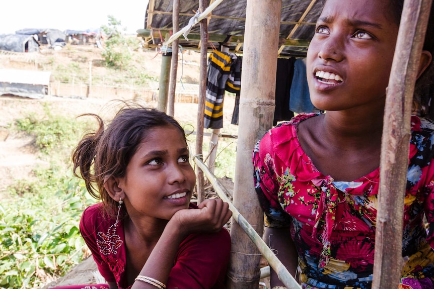 Two young girls inside a makeshift hut