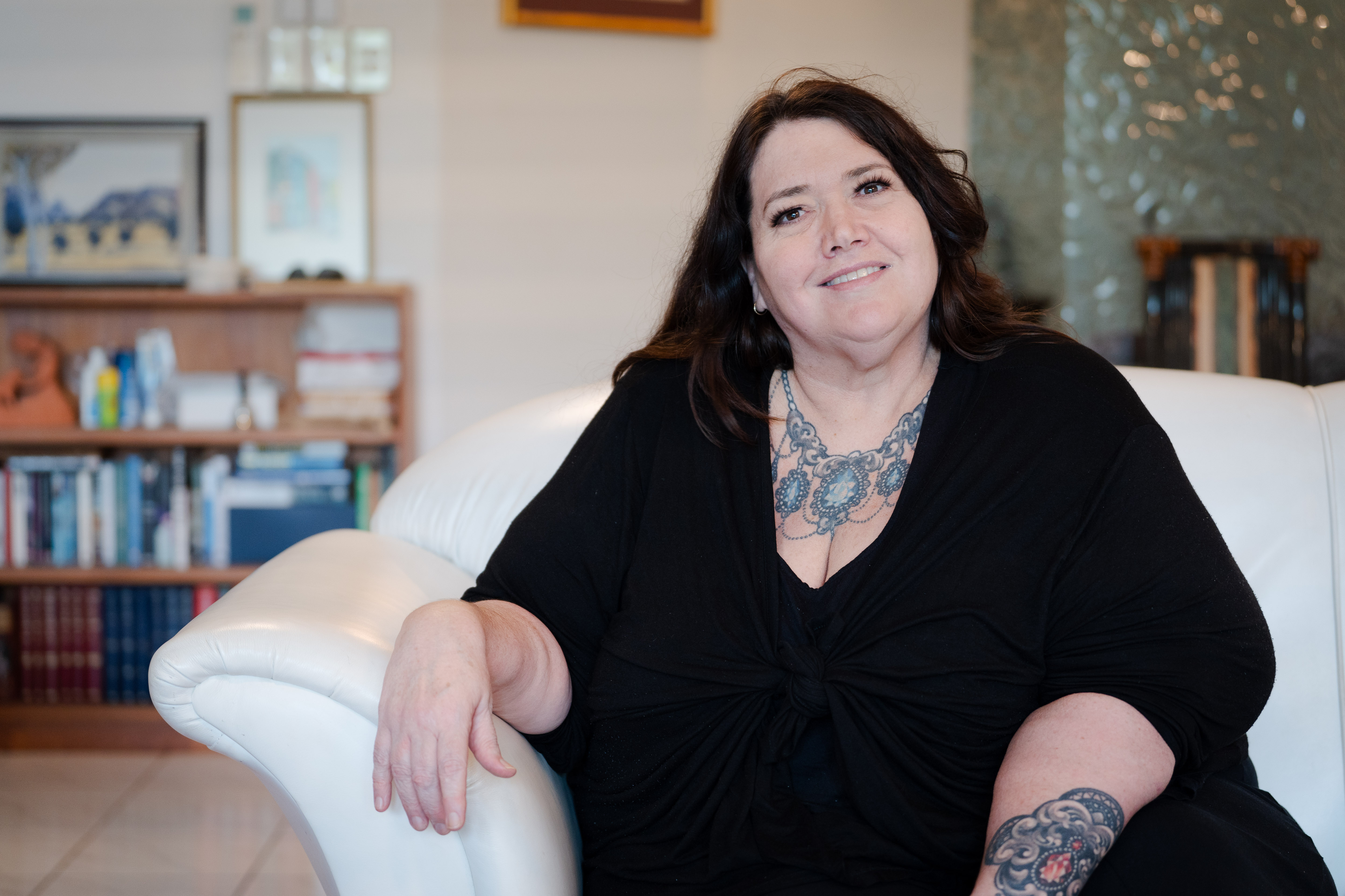 Uma mulher vestindo uma camisa escura sorri para a câmera.