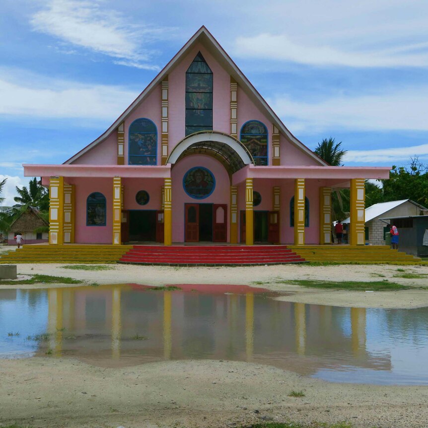 A pink Church with a big puddle outside