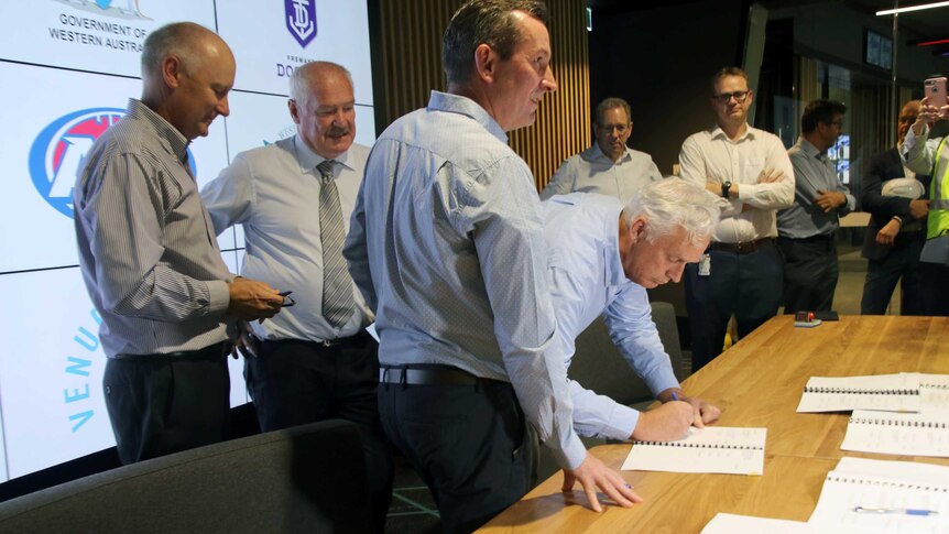 WAFC chairman Murray McHenry signs a Perth Stadium agreement surrounded by Premier Mark McGowan and others.