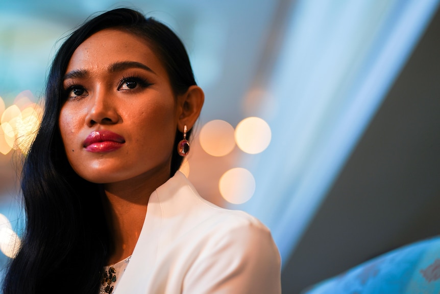 A Myanmar woman with her hair swept to one side looks out beyond the camera with a serious expression.