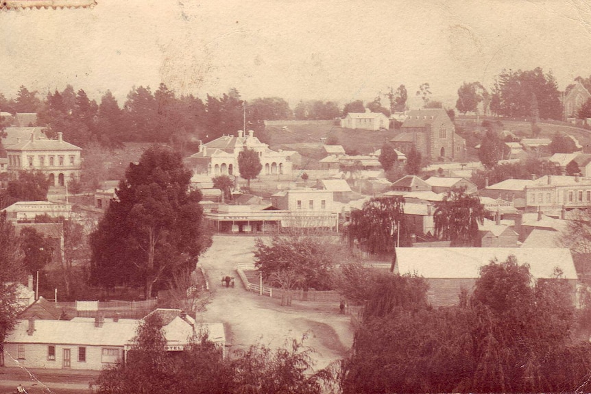 Old, sepia-toned photograph of a town, showing several buildings, streets and garden areas.