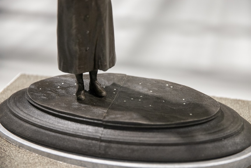small silver spots on the brown base of the statue around her feet