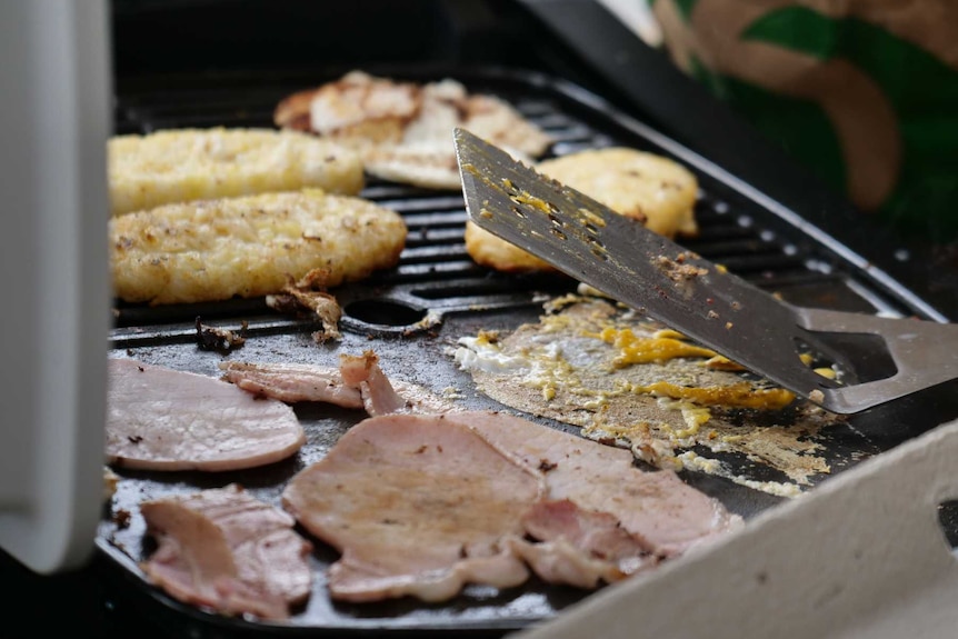 hash browns, bacon, egg on a barbcue grill with a spatula