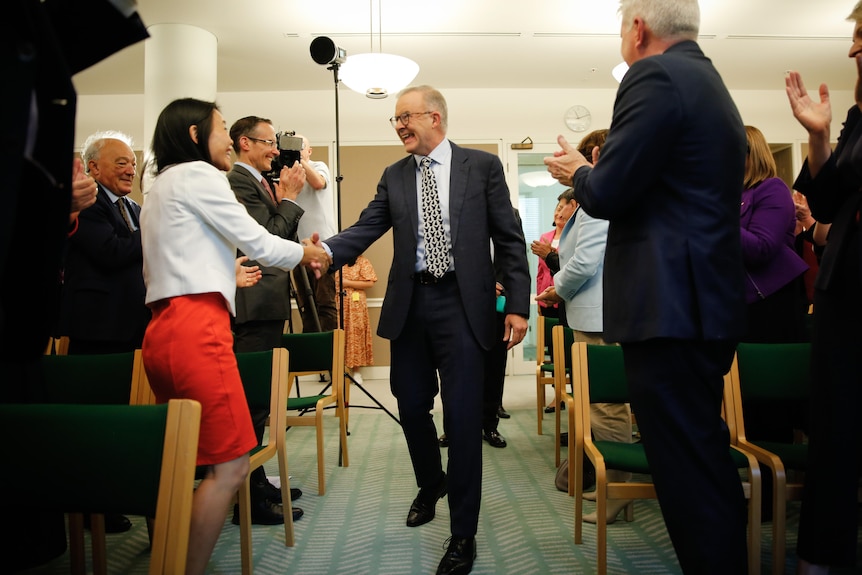 Prime Minister Anthony Albanese shakes hands of Labor members of parliament at the first caucus meeting since the election.