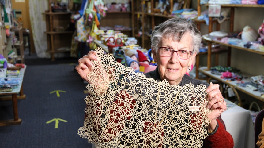 A woman holds an original piece of lace tatting.