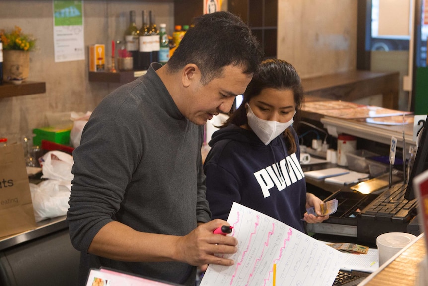 a man and woman at a restaurant counter going over notes and documents