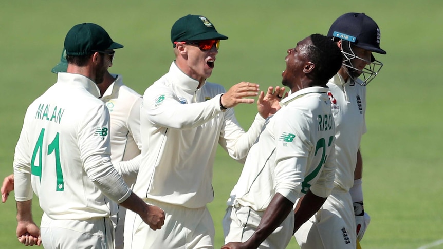 Kagiso Rabada screams in the air. South African teammates come to him in joy. Joe Root walks past sadly.