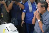 Cambodian Prime Minister Hun Sen (R) kisses a ballot at a polling station
