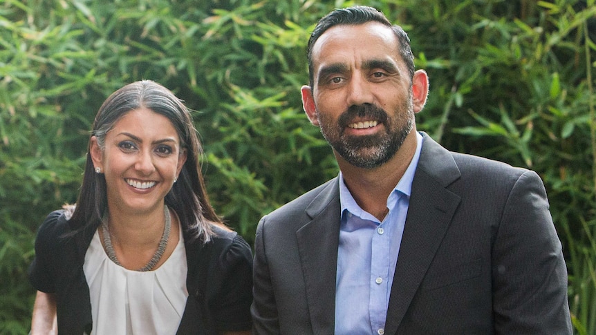 Two people facing camera, smiling, in an outdoor setting.