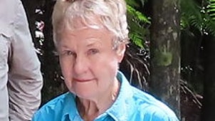 an elderly woman with short grey hair wearing a blue shirt