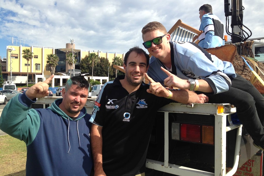 Three Cronulla fans hold their fingers as number one.