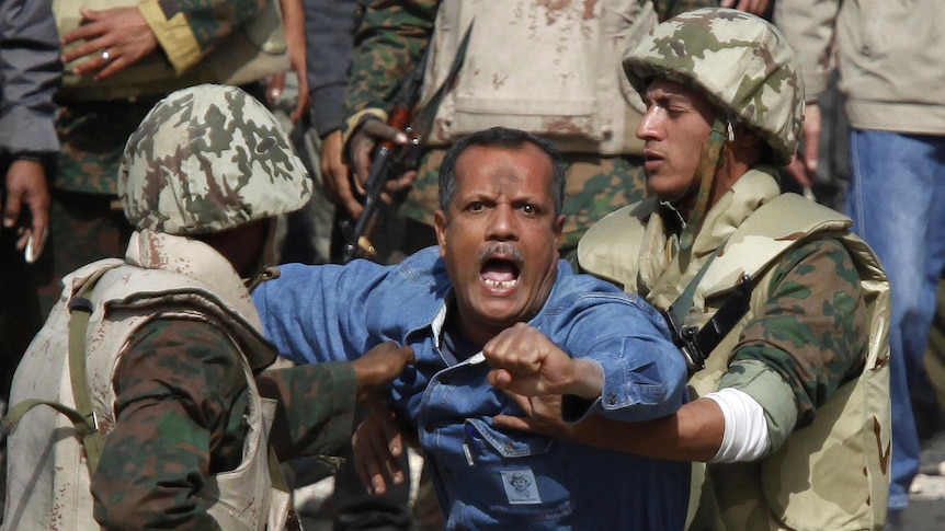 Egyptian soldiers restrain a supporter of Hosni Mubarak