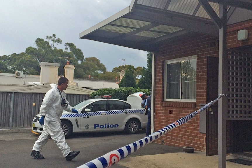 Forensic police outside a property cordoned off by police tape.