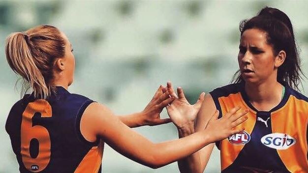 two women AFL payers giving each on the High fives on the field