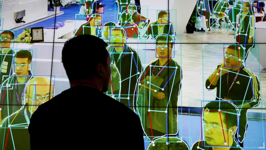 A man looks at a demonstration on a big screen of software tracking the movement of people.