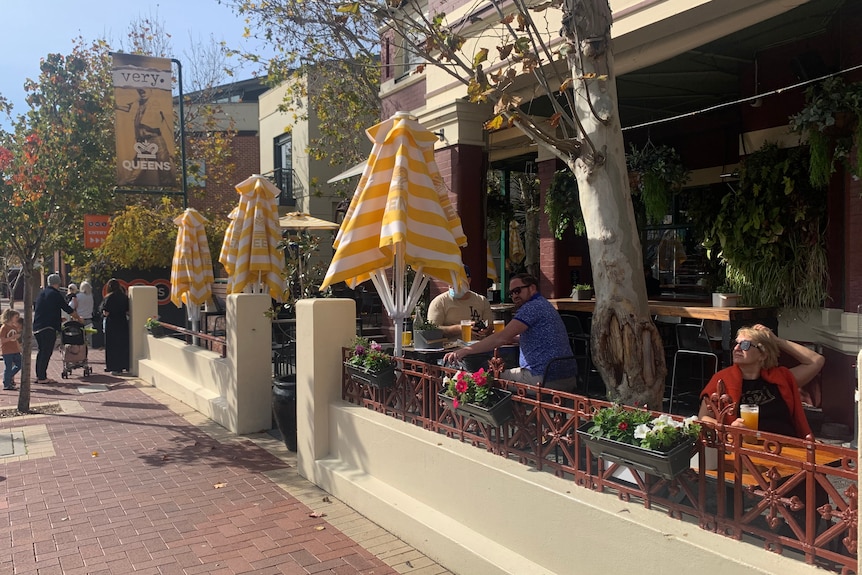 People sitting outside a pub in the sunshine.