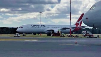 A Qantas plane parked on the tarmac at an airport.