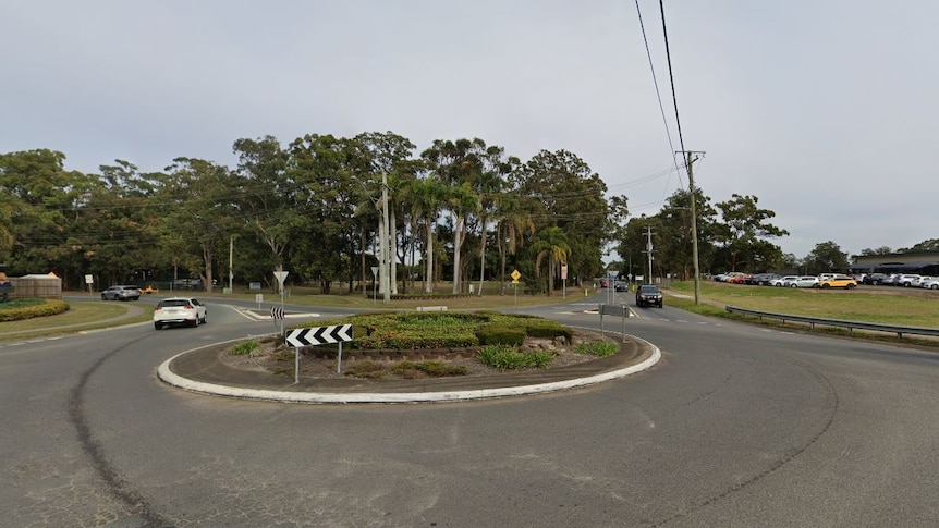 A small, old roundabout with several cars driving through it.