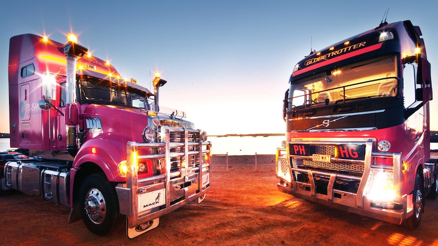 Two pink trucks face each other at sunset in the outback.
