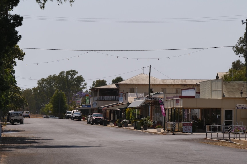 A shot down a main street of a small town, an old two-storey hotel sits beside a wide bitumen road