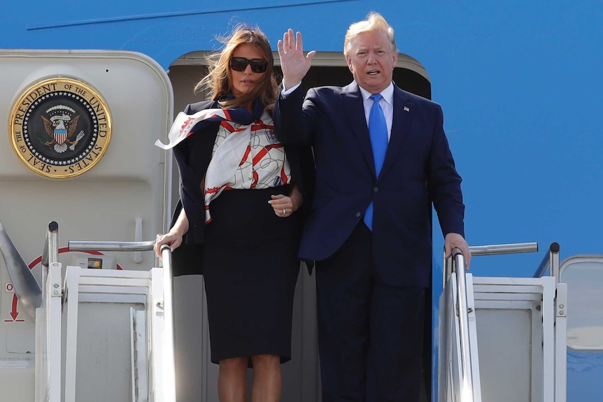 Donald Trump waves while Melania stands along side him atop the stairs outside Air Force One.