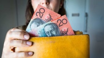 Woman holding a wallet with 20 dollar bills.