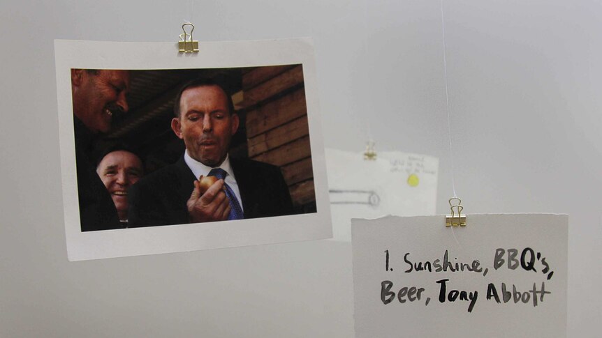 A photo of Tony Abbott eating an onion, and another small placard that reads, 'sunshine, BBQ's, beer, Tony Abbott.'
