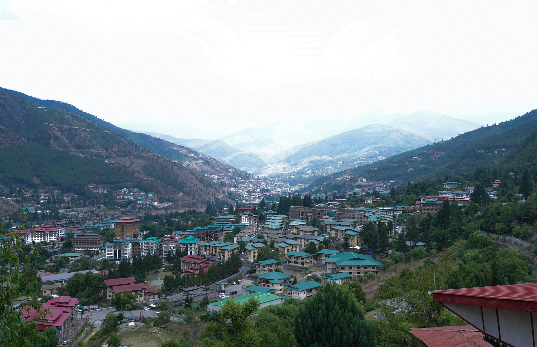 Edifícios espalhados por uma paisagem com montanhas ao fundo.