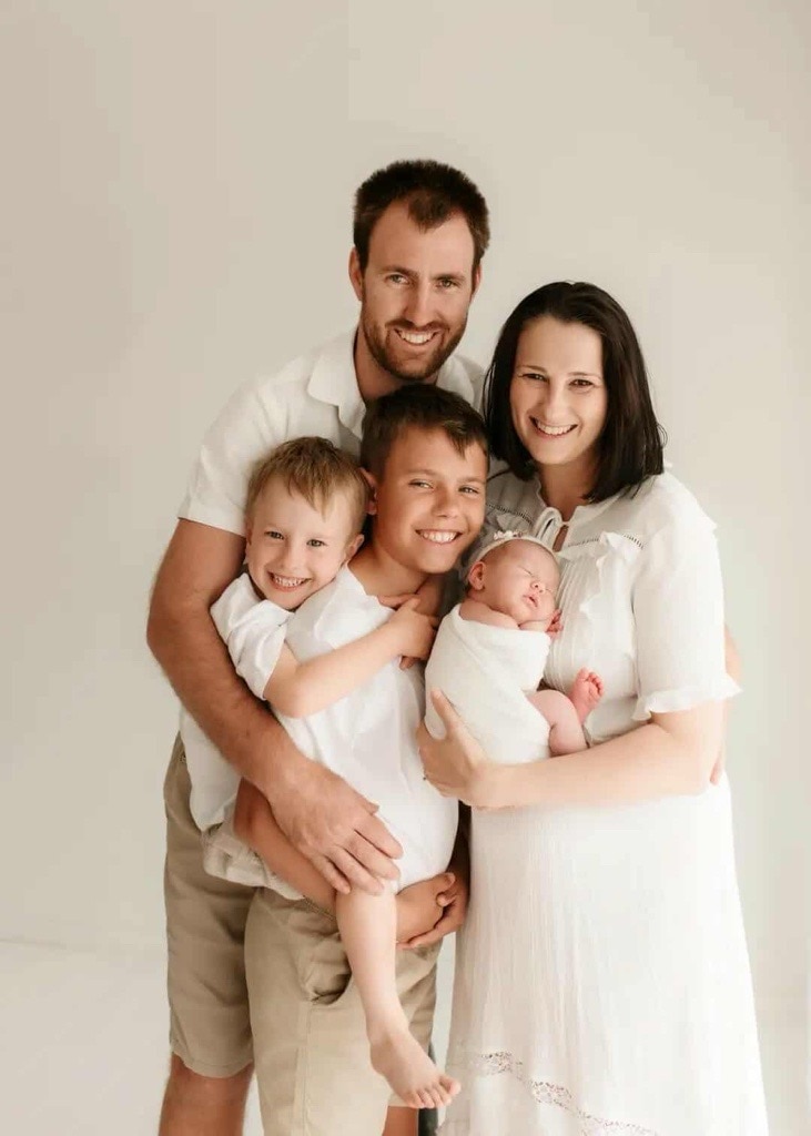 Aaron sorrindo para a câmera com sua esposa Tahnee e três filhos. 