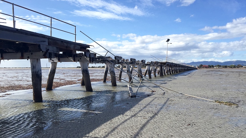 A section of wooden jetty with bent metal and stripped of wood due to storm damage.