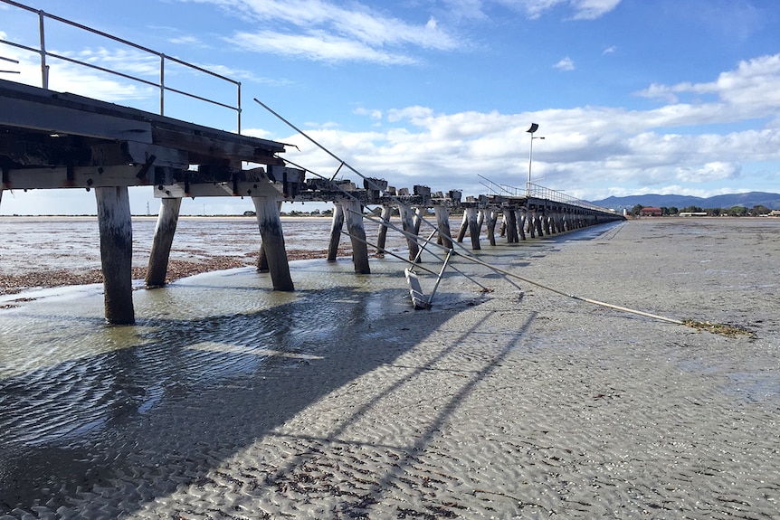 A section of wooden jetty with bent metal and stripped of wood due to storm damage.