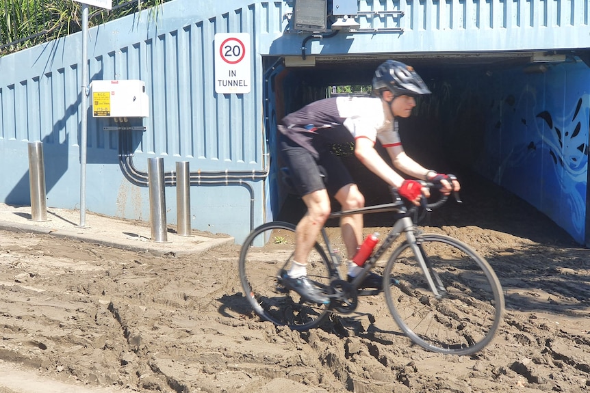 a cyclist rides through thick mud on a bikeway