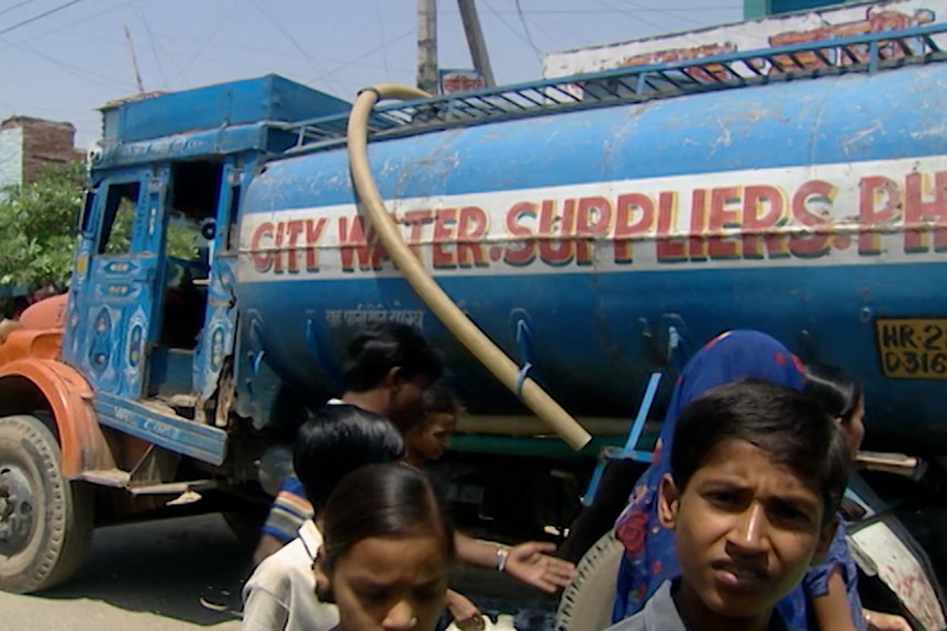 People in Chennai crowd around a water truck.